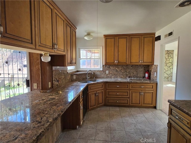 kitchen with tasteful backsplash, a sink, visible vents, and brown cabinets