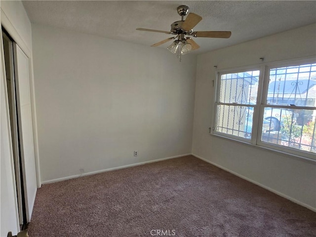 carpeted empty room featuring a textured ceiling, baseboards, and a ceiling fan