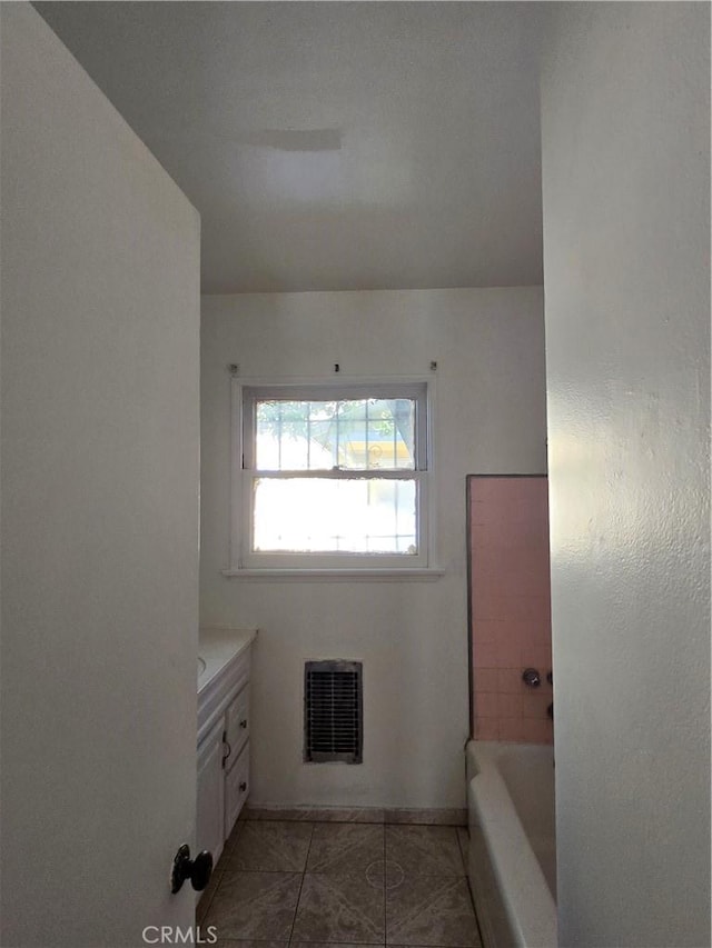 full bathroom with a washtub, vanity, tile patterned flooring, and visible vents