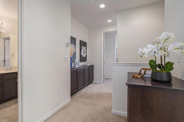 hallway featuring sink and light carpet