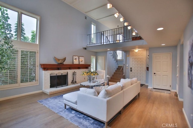 living room with a fireplace, a towering ceiling, and light hardwood / wood-style floors