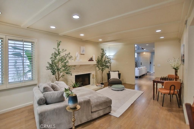 living room featuring beamed ceiling, wood-type flooring, a fireplace, and ornamental molding