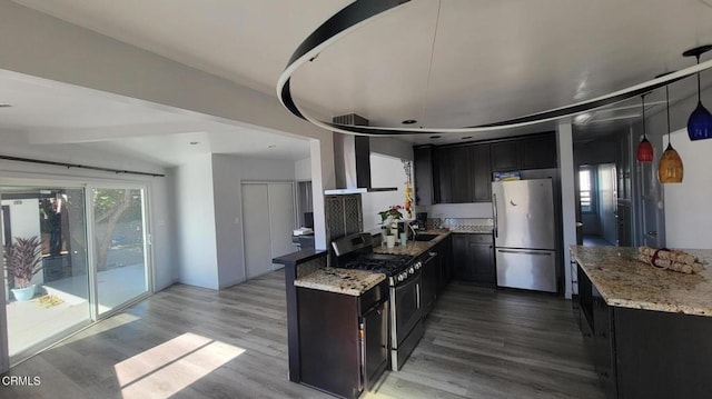 kitchen featuring stone counters, appliances with stainless steel finishes, light wood-type flooring, and wall chimney exhaust hood