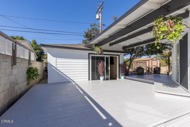 view of patio featuring a wooden deck and a storage unit