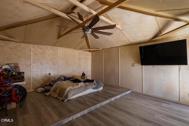 unfurnished bedroom featuring lofted ceiling with beams, a decorative wall, and wood finished floors