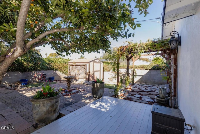 deck with a patio area, a fenced backyard, a shed, and an outdoor structure