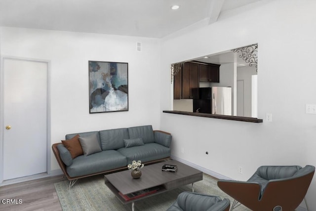 living room with recessed lighting, beamed ceiling, light wood-style flooring, and baseboards