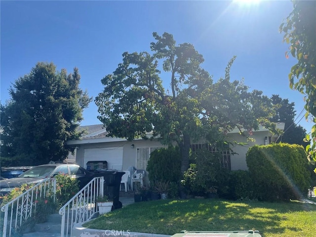 view of property hidden behind natural elements with a front yard and a garage