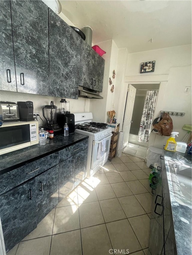 kitchen with tile patterned flooring, white appliances, and extractor fan