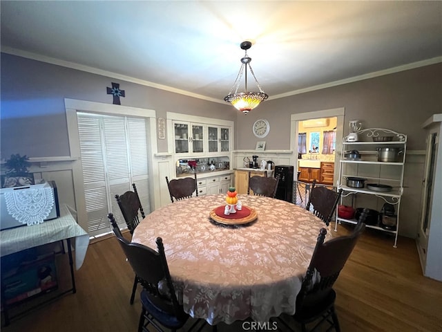 dining space featuring dark hardwood / wood-style floors, crown molding, and sink