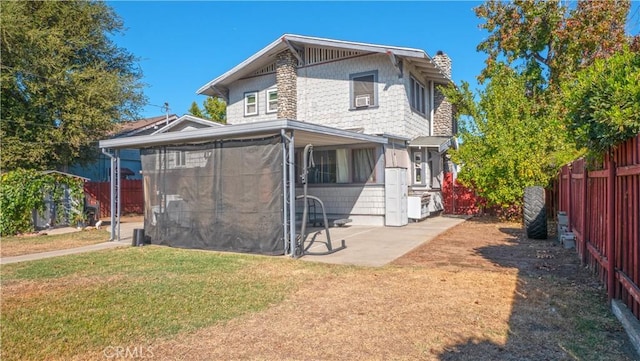 back of house with a lawn and a patio