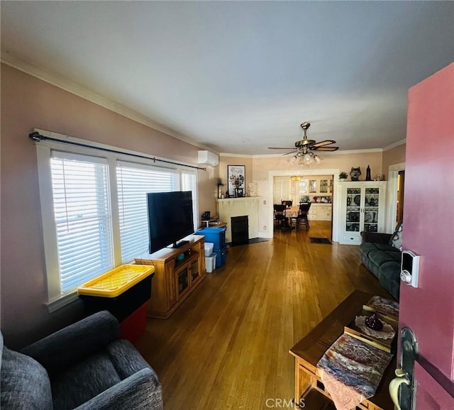 living room featuring ceiling fan, wood-type flooring, ornamental molding, and a wall unit AC