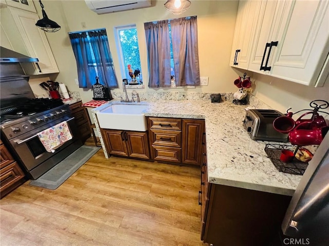 kitchen featuring high end range, sink, light wood-type flooring, a wall unit AC, and extractor fan