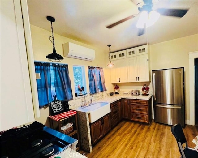 kitchen featuring white cabinets, pendant lighting, an AC wall unit, and stainless steel refrigerator