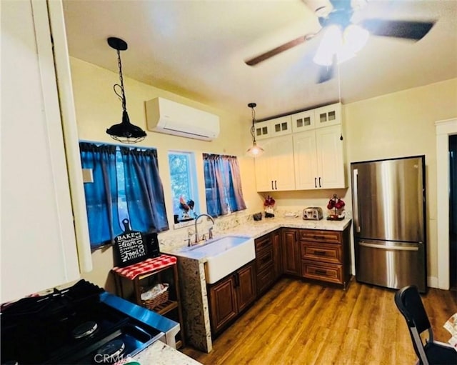 174 E Navilla Pl, Covina, CA 91723 - kitchen with freestanding refrigerator, a wall unit AC, white cabinets, wood finished floors, and pendant lighting