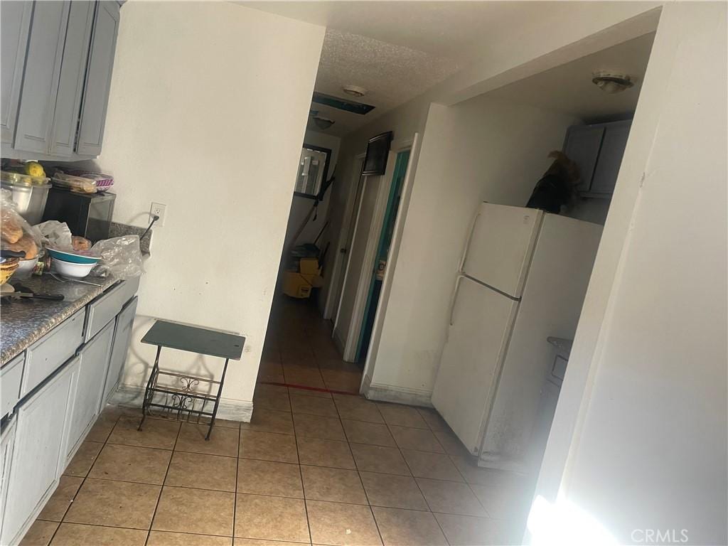 kitchen with gray cabinetry, light tile patterned floors, and white refrigerator