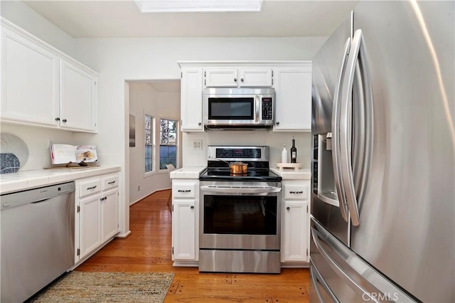 kitchen featuring white cabinets, stainless steel appliances, tile counters, and light hardwood / wood-style floors