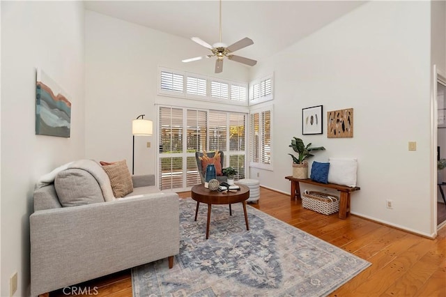 living room featuring a towering ceiling, hardwood / wood-style flooring, and ceiling fan