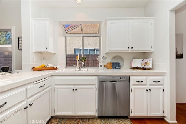 kitchen with white cabinets, dark hardwood / wood-style floors, stainless steel dishwasher, and tile counters