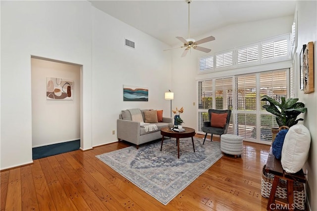 living room with ceiling fan, wood-type flooring, and high vaulted ceiling