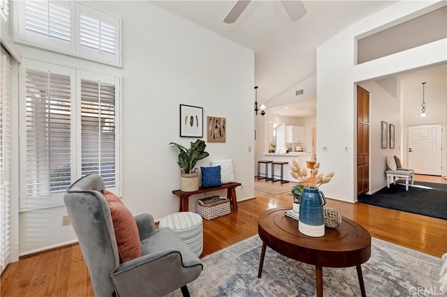 living room with ceiling fan, light wood-type flooring, and high vaulted ceiling