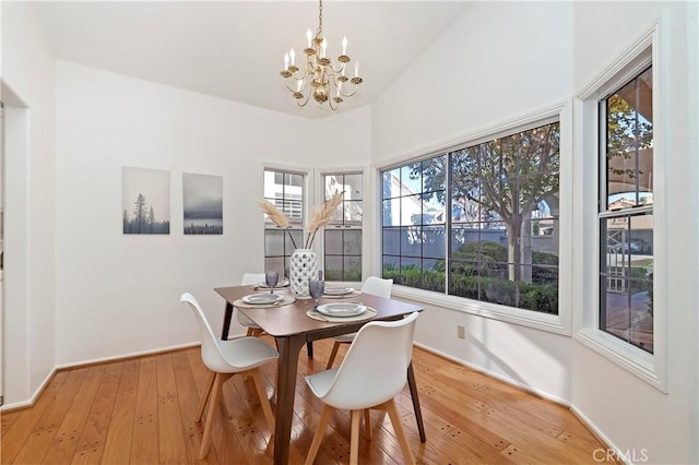 dining room with light wood-type flooring, plenty of natural light, and a notable chandelier