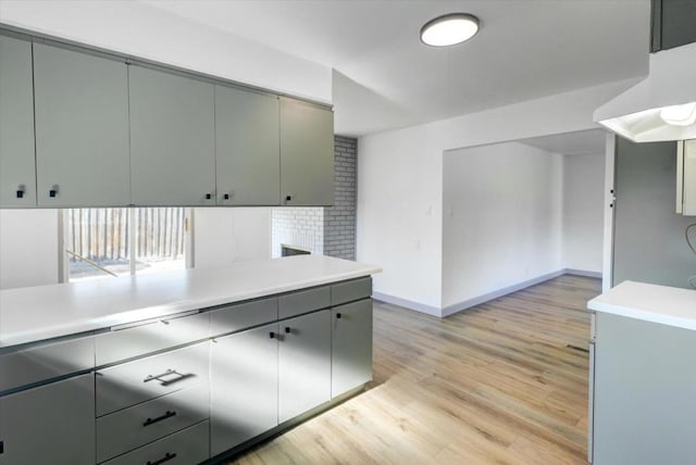 kitchen with decorative backsplash, light hardwood / wood-style floors, kitchen peninsula, and gray cabinets