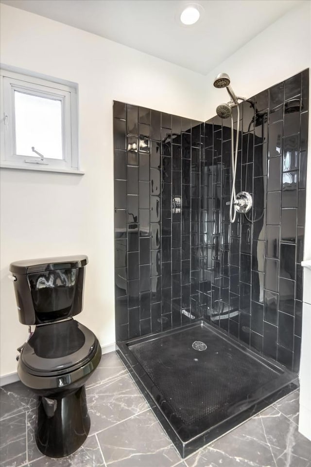 bathroom featuring tiled shower and toilet