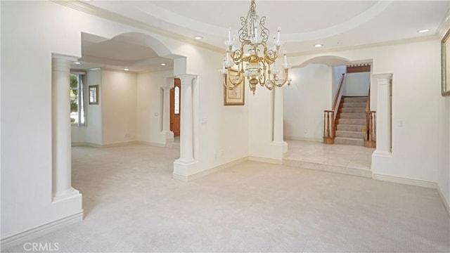 carpeted empty room with a raised ceiling, an inviting chandelier, and ornamental molding