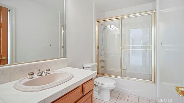 full bathroom with combined bath / shower with glass door, vanity, tile patterned flooring, and toilet