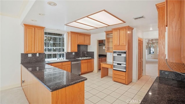 kitchen with backsplash, kitchen peninsula, dark stone countertops, light tile patterned floors, and appliances with stainless steel finishes