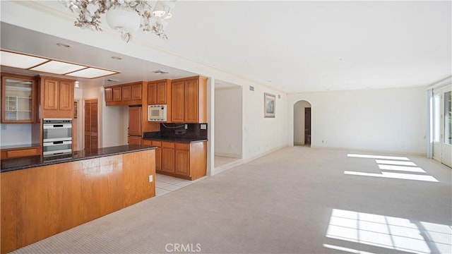 kitchen featuring light carpet, tasteful backsplash, stainless steel double oven, white microwave, and an inviting chandelier