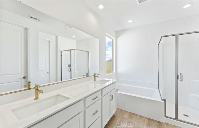 full bathroom with visible vents, a sink, a shower stall, and wood finished floors