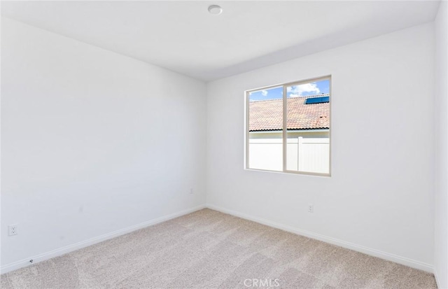 empty room with baseboards and light colored carpet