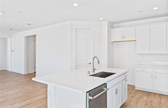 kitchen with white cabinets, light countertops, light wood-type flooring, a sink, and recessed lighting