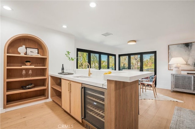 bar with wine cooler, sink, and light hardwood / wood-style floors