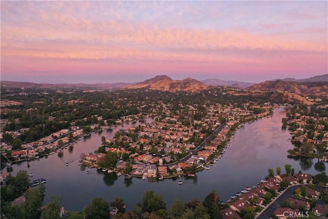 aerial view at dusk featuring a water and mountain view