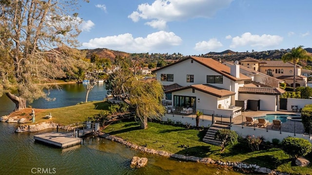 back of property featuring a lawn and a water and mountain view