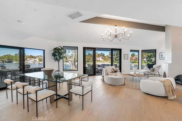 dining room with light hardwood / wood-style flooring, a water view, and an inviting chandelier