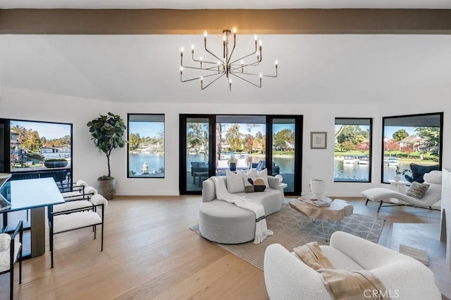 living room featuring a water view, beamed ceiling, light hardwood / wood-style floors, and an inviting chandelier