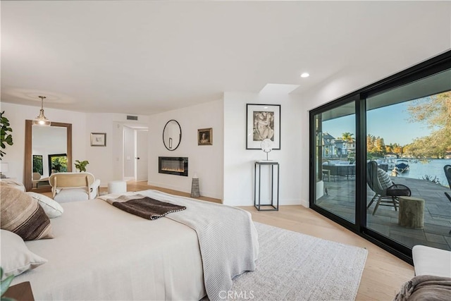 bedroom featuring access to exterior, light hardwood / wood-style flooring, and multiple windows