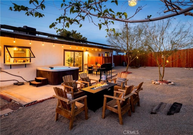 view of patio / terrace with a fire pit, fence, and a hot tub