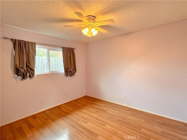 spare room featuring a textured ceiling, light wood-type flooring, and ceiling fan