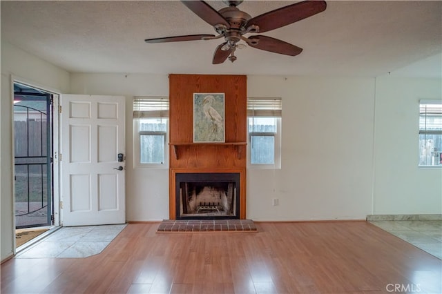 unfurnished living room with a wealth of natural light, light hardwood / wood-style flooring, and a textured ceiling