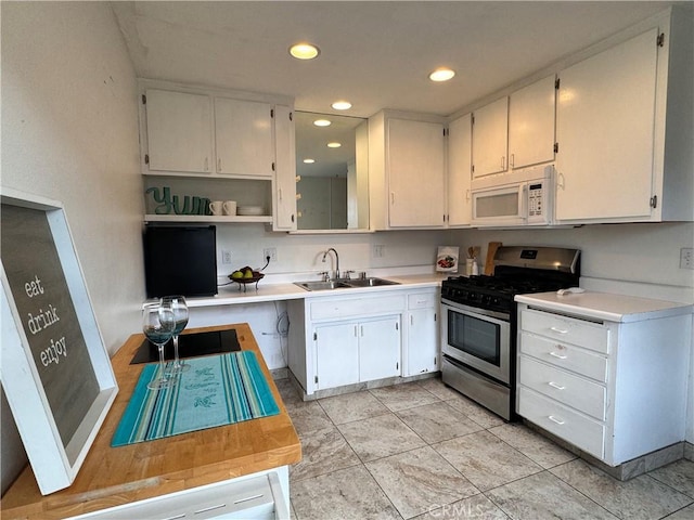 kitchen featuring white cabinetry, stainless steel gas range oven, and sink