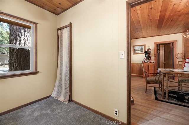 hallway featuring light wood-type flooring, wood walls, and wood ceiling