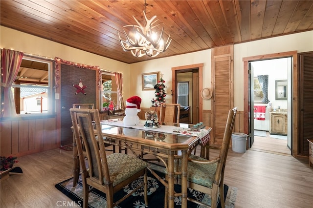 dining space featuring hardwood / wood-style floors, wooden ceiling, wooden walls, and an inviting chandelier