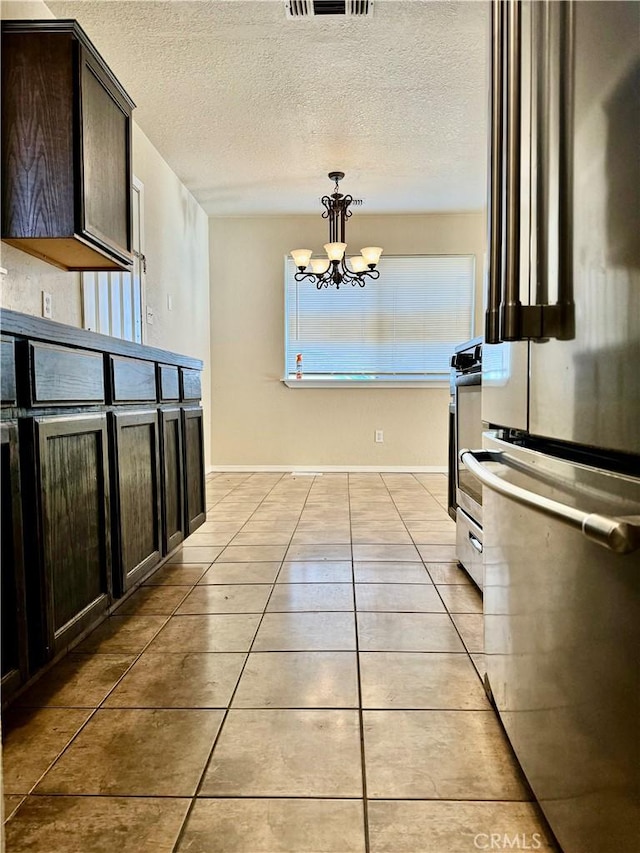 kitchen featuring appliances with stainless steel finishes, dark brown cabinetry, pendant lighting, a chandelier, and light tile patterned flooring