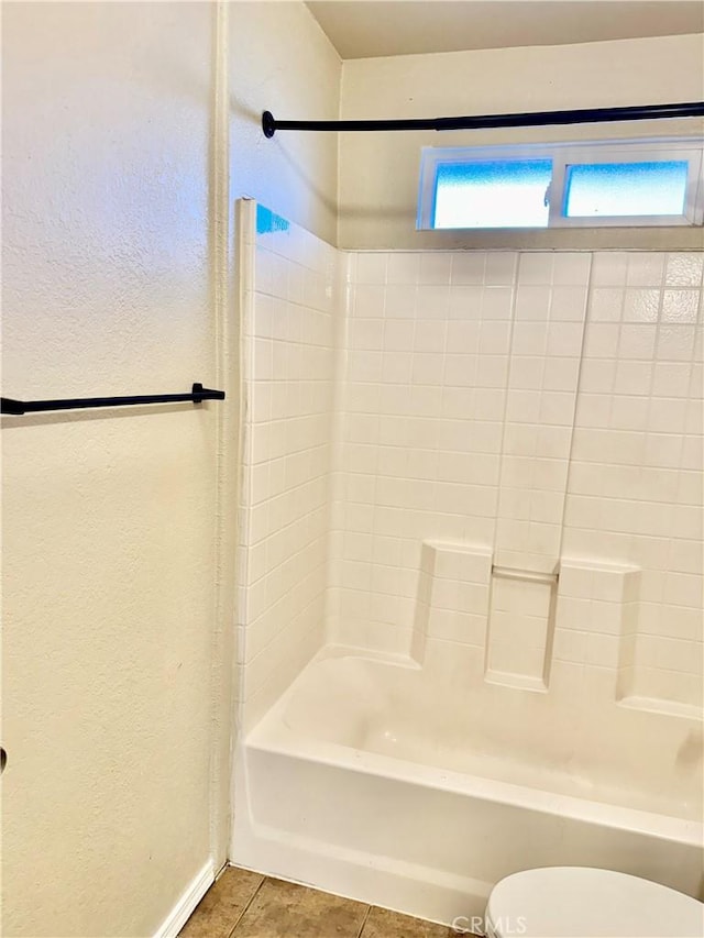 bathroom with tile patterned flooring, shower / bathtub combination, and toilet