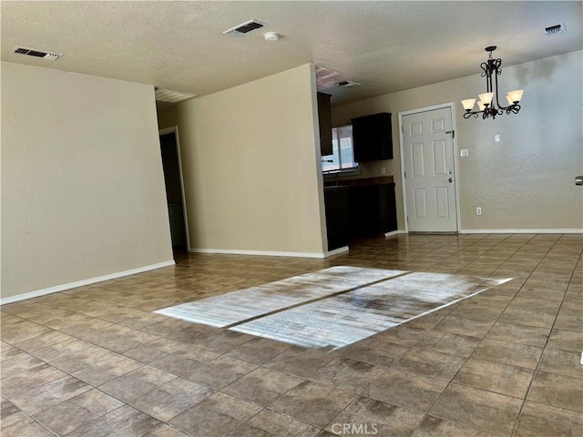 spare room featuring a notable chandelier and a textured ceiling